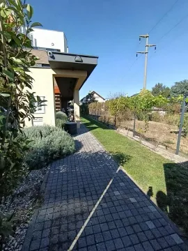 Paved walkway next to the house with a landscaped yard and lawn. - image 2