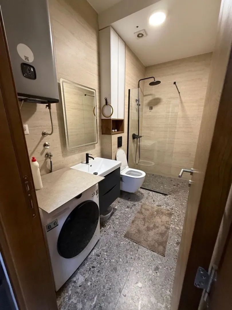 Moderno opremljeno kupatilo sa tuš kabinom, umivaonikom i veš mašinom.