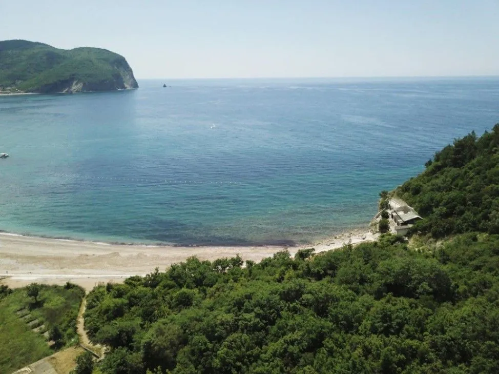 Pogled iz vazduha na uvalu, plažu i šumu pored mora.