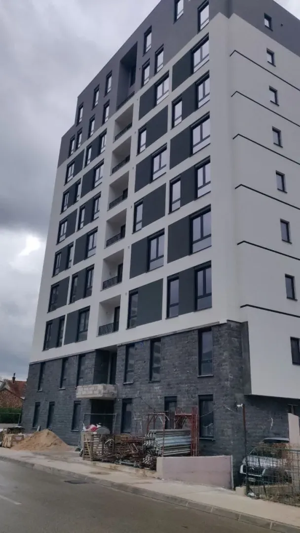 Moderno izgrađena stambena zgrada sa sivom i bijelom fasadom.
