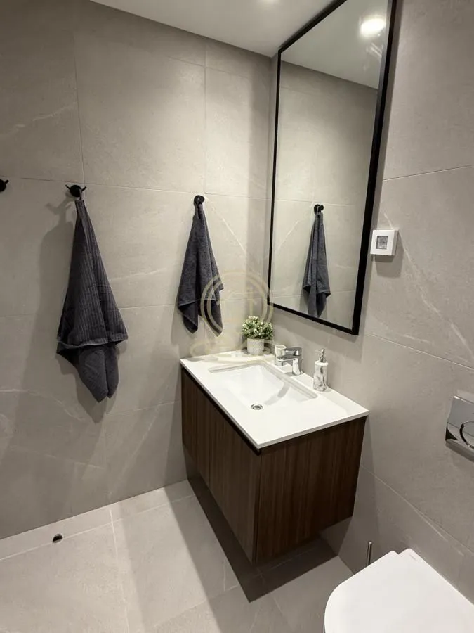 Modern bathroom with a vanity, mirror, and grey tiles.
