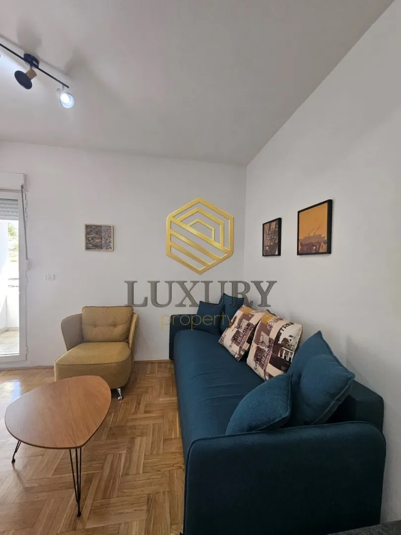 Living room with a blue sofa, yellow armchair, and parquet flooring.