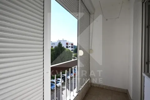 Covered balcony with roller shutters and a view of surrounding buildings and parking. - image 25