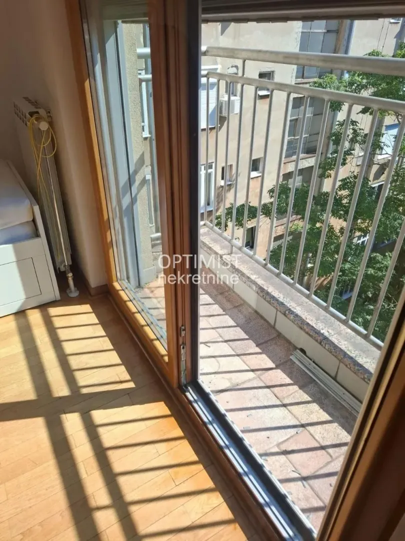 Pogled kroz balkonska vrata na manji spoljni balkon sa metalnom ogradom.