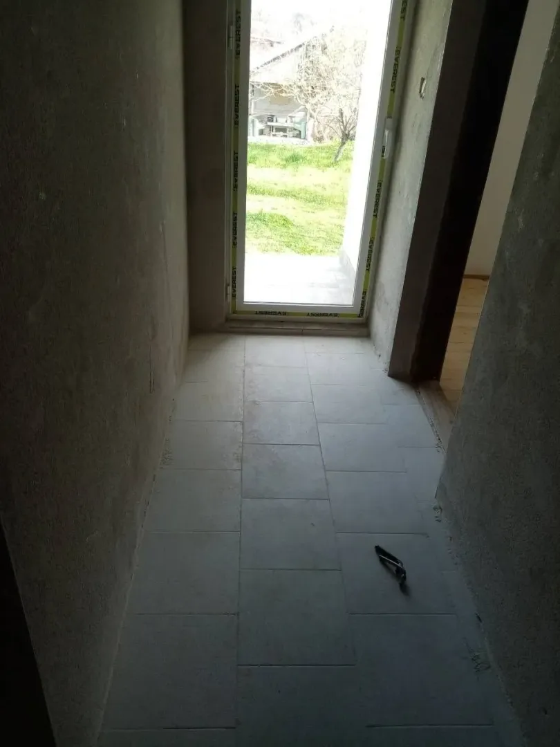 An unfinished hallway with tiled flooring and a view of the yard.