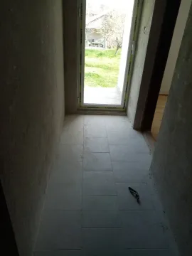 An unfinished hallway with tiled flooring and a view of the yard. - image 10