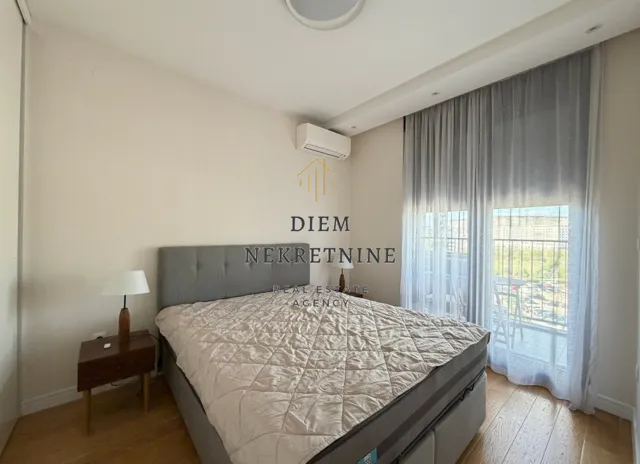 Bright and tidy bedroom with a double bed, nightstand, and terrace access.