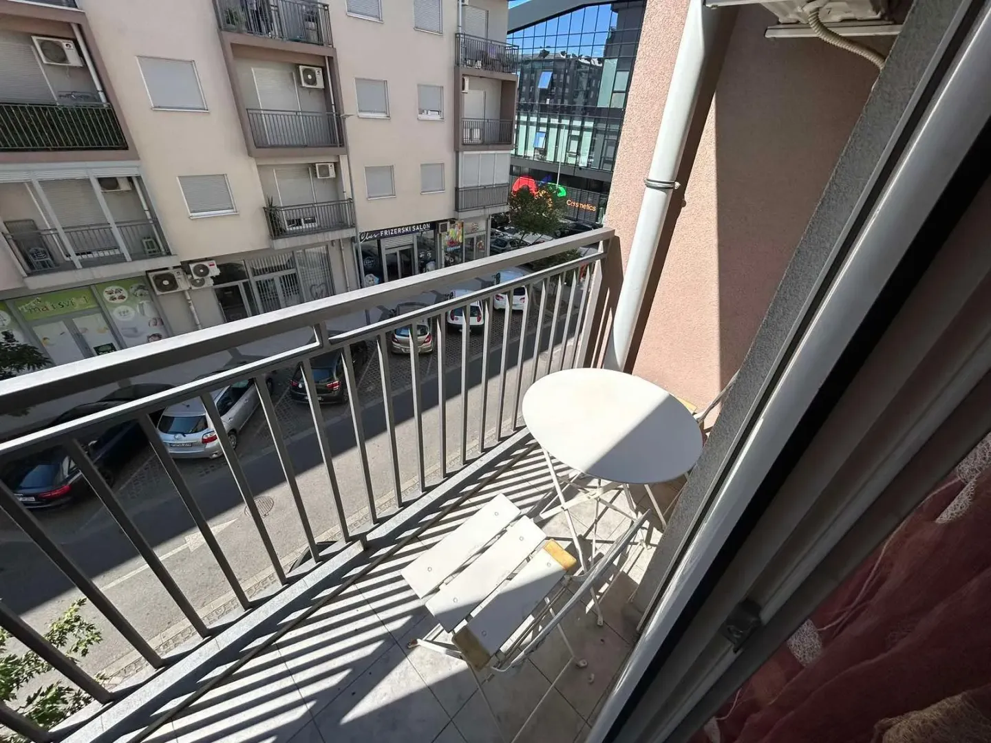 Manji namješteni balkon sa stolom i stolicama i pogledom na ulicu.