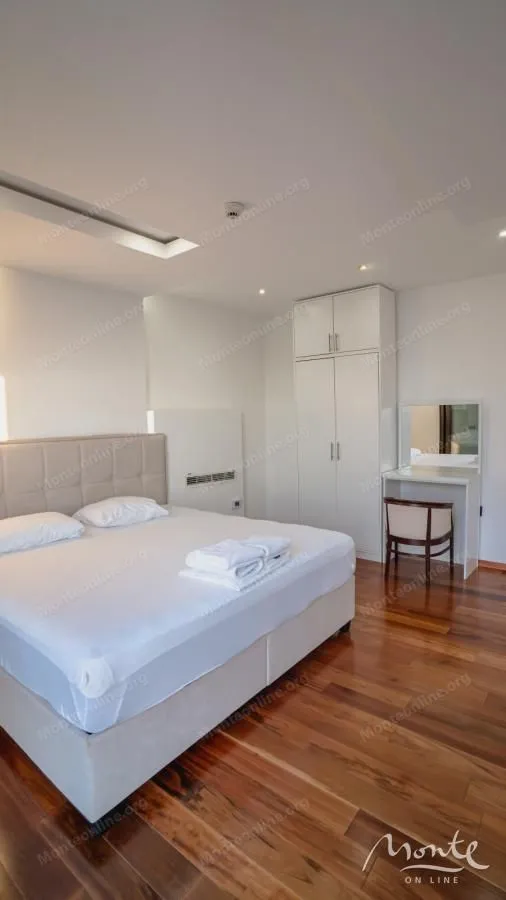 Bedroom with a double bed, a white wardrobe, and a vanity desk with a mirror.