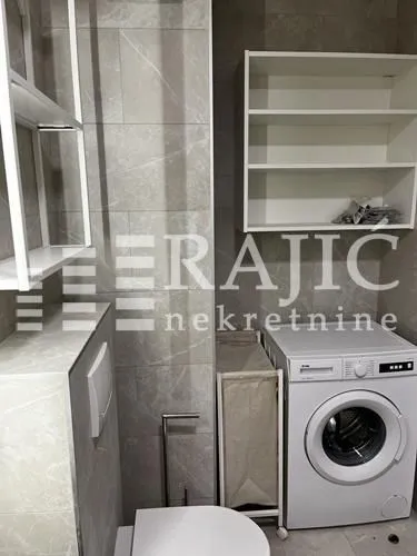 Modern bathroom with washing machine and white shelves.