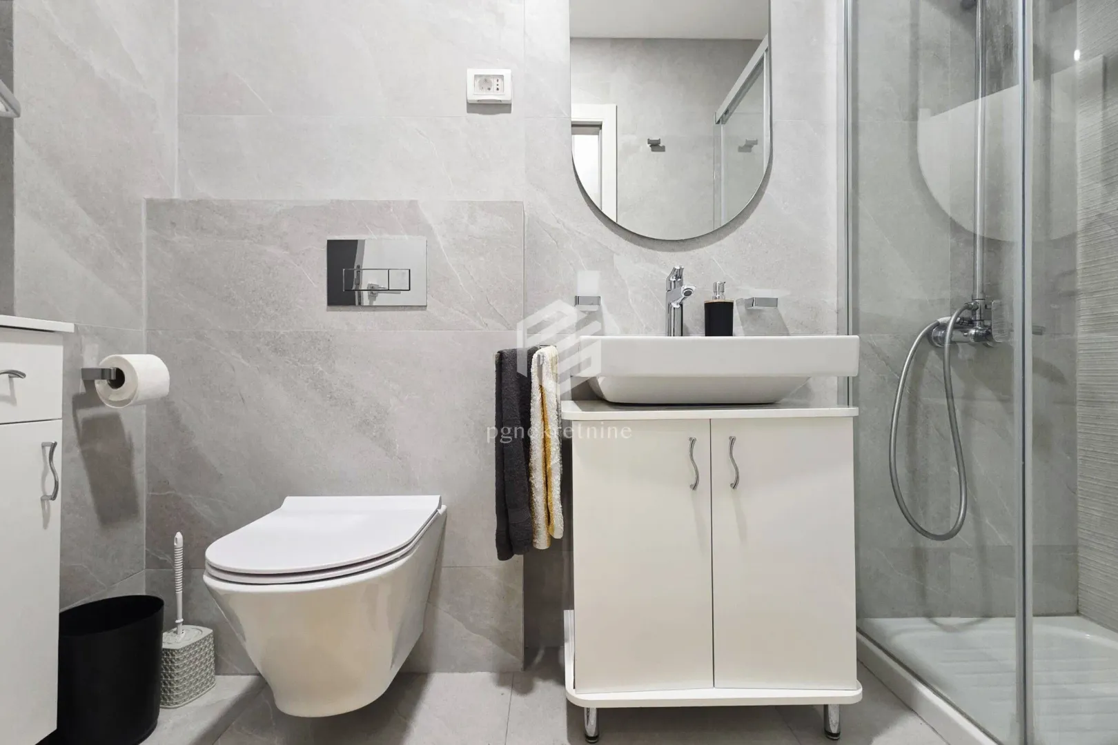 Modern bathroom equipped with a walk-in shower, washbasin, and mirror.