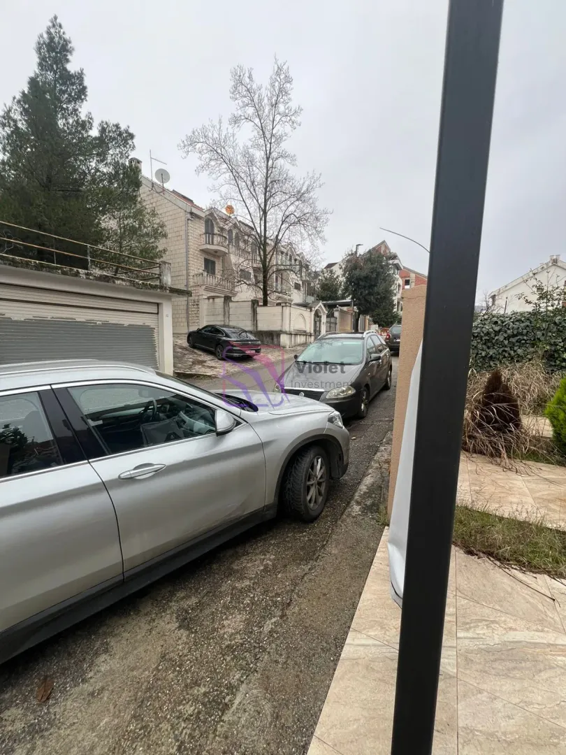Pogled na ulicu i spoljašnji dio objekta sa parkiranim automobilima.