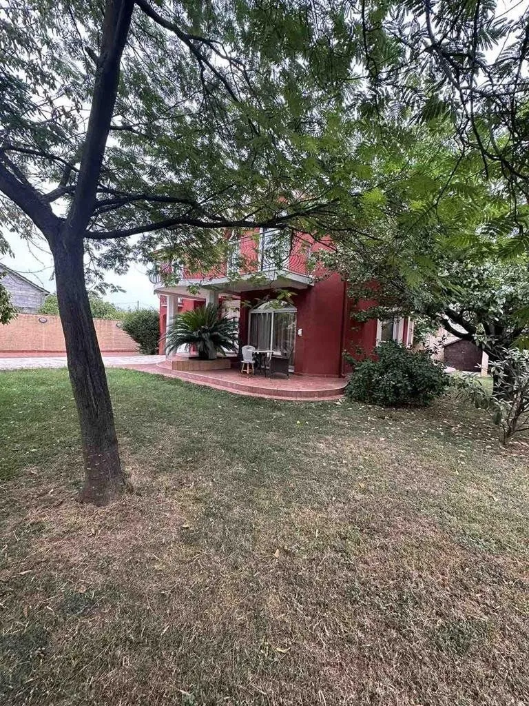 View of the yard and the facade of the house surrounded by greenery and trees.