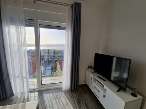 Dnevna soba sa TV komodom i izlazom na terasu sa pogledom na more. - image 10