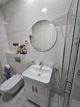 Moderno opremljeno kupatilo sa umivaonikom, konzolnom šoljom i okruglim ogledalom. - image 6