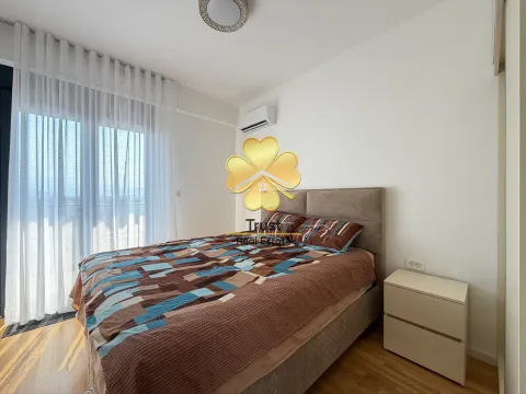 Bright bedroom with a double bed, white bedside table, and balcony doors. - image 12