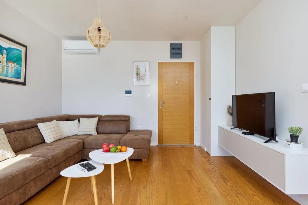 Living room with a sofa, TV, and wooden flooring.