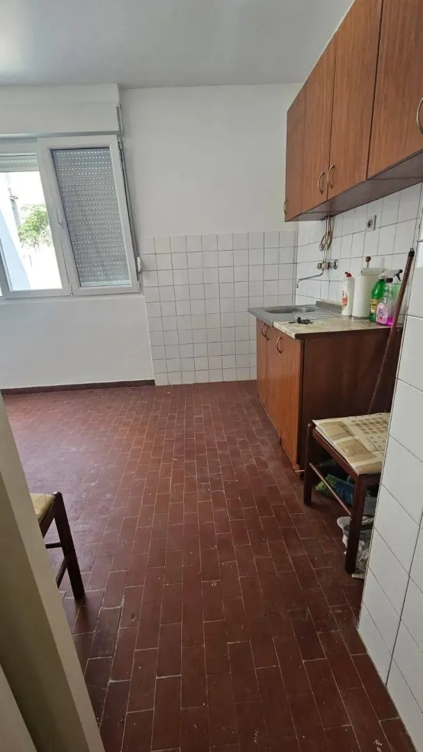 Manja kuhinja sa drvenim elementima i pločicama na podu.