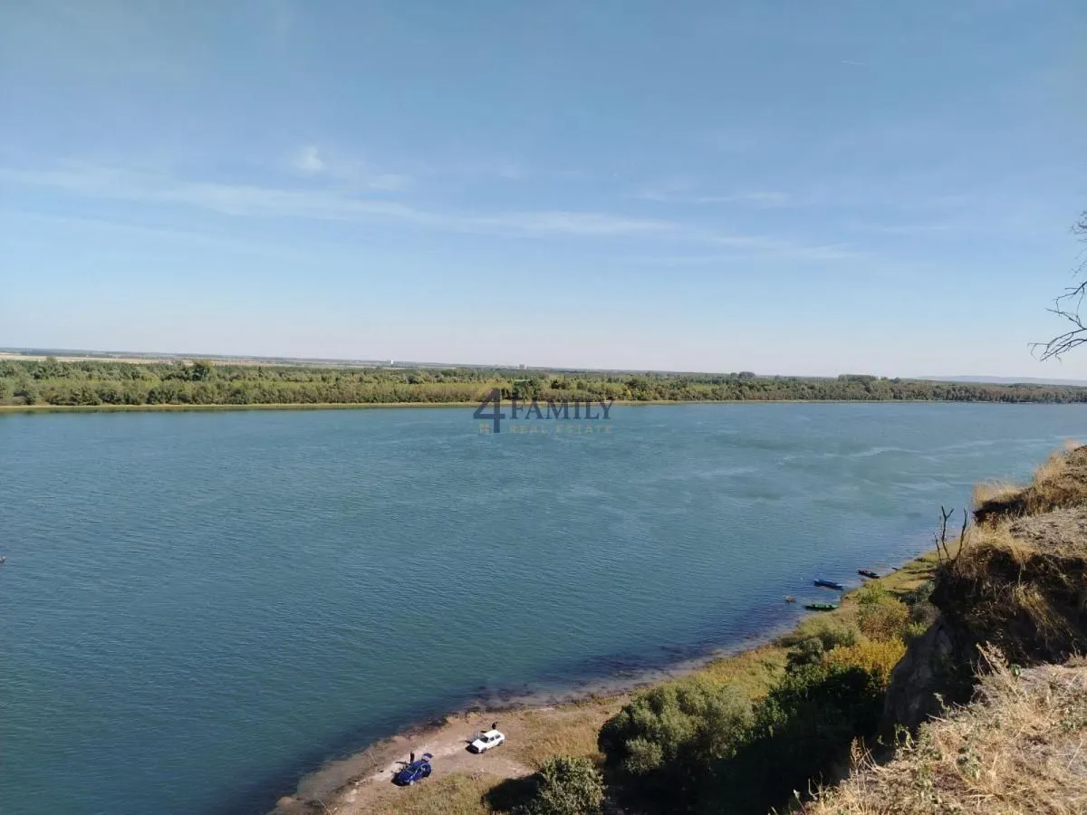 Pogled na reku sa visoke obale sa vodenim prostranstvom u pozadini.