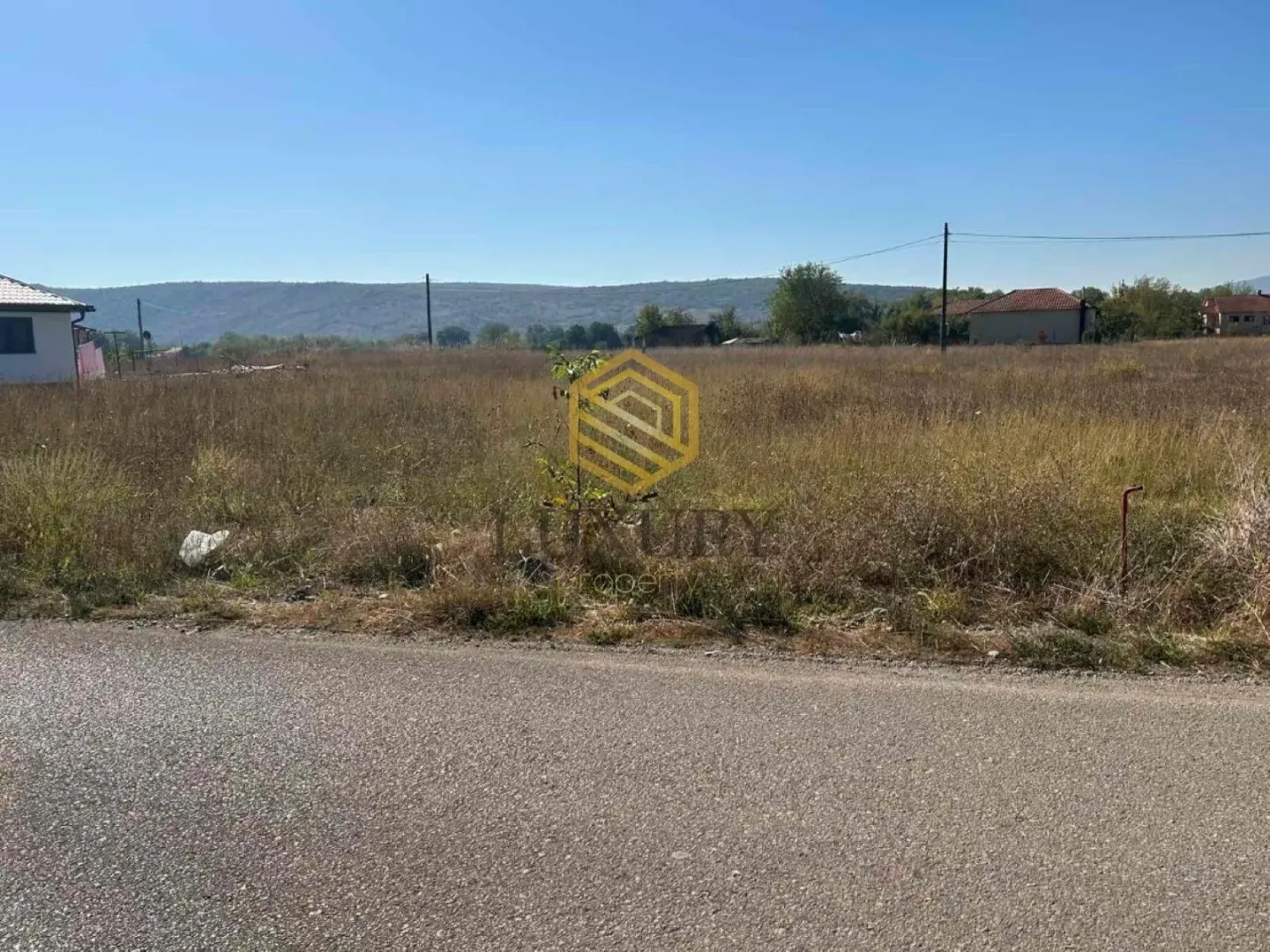 Pogled na zemljište i put pored placa sa vodenim žigom agencije.