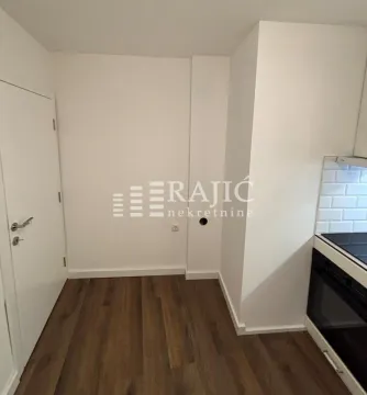 Part of the kitchen with white tiles and a wooden floor. - image 11