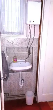 Small bathroom with a sink, water heater, and wall tiles. - image 9