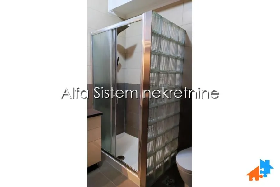 Bathroom with a shower cabin and a glass block partition wall.