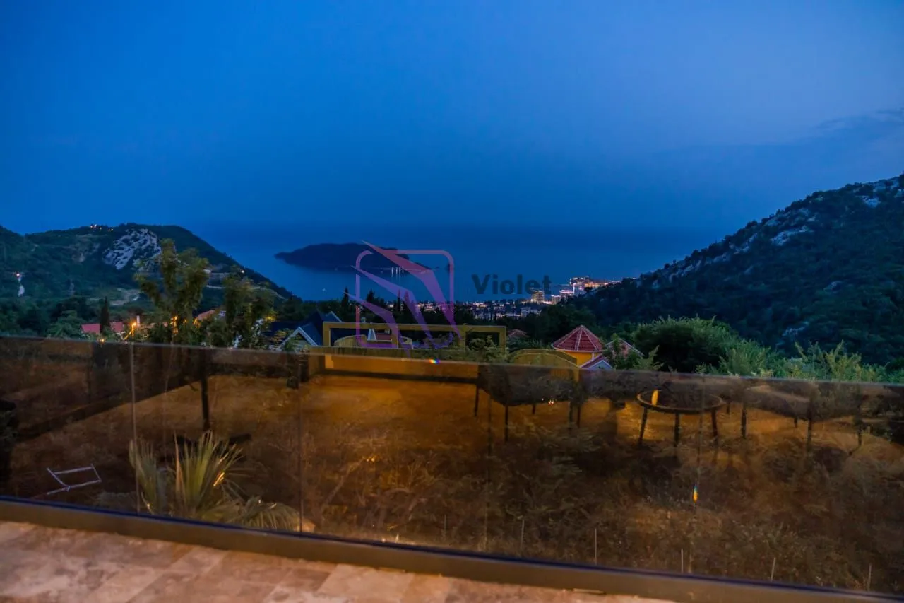 View of the sea and surrounding mountains at dusk.