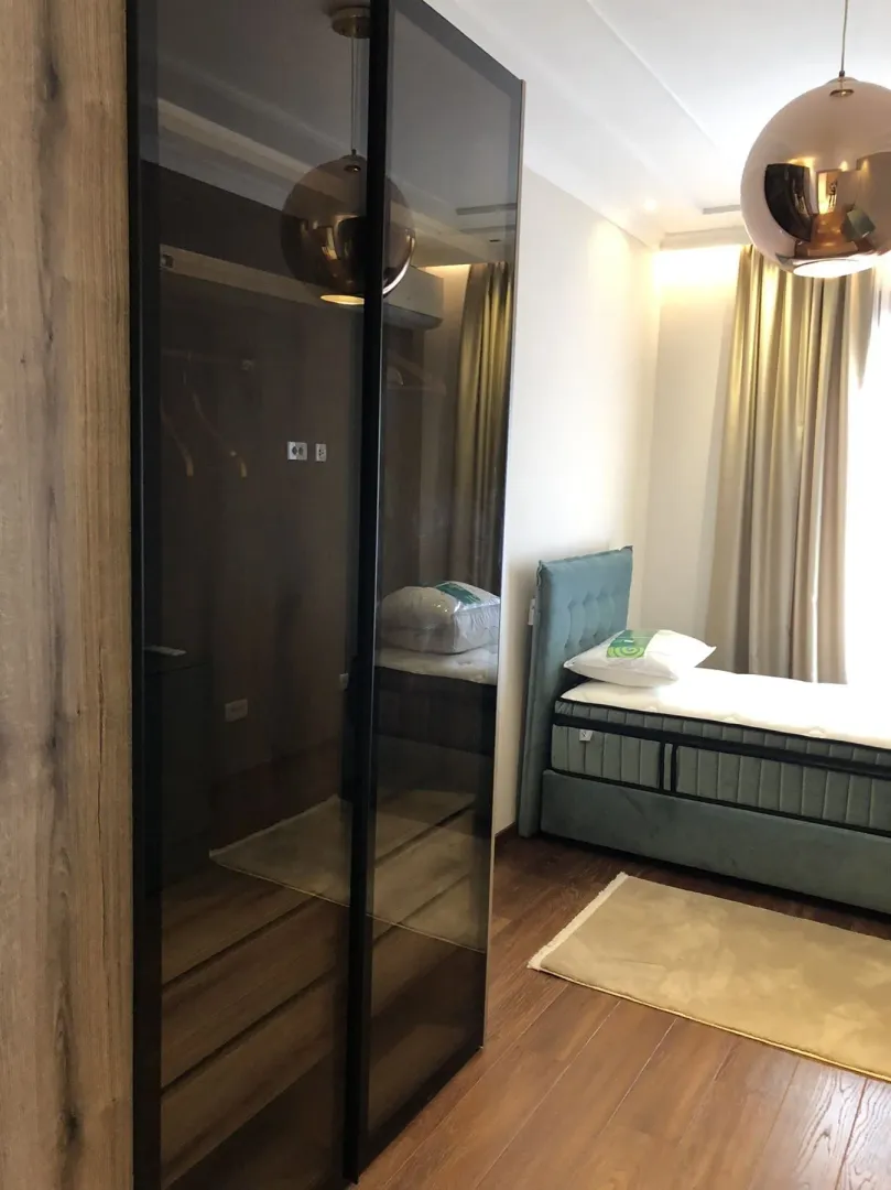 Bright bedroom with a modern bed and a built-in wardrobe.