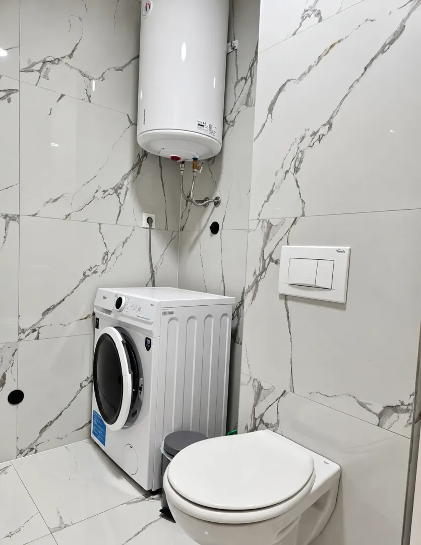 Bathroom with a washing machine, concealed cistern, and water heater.