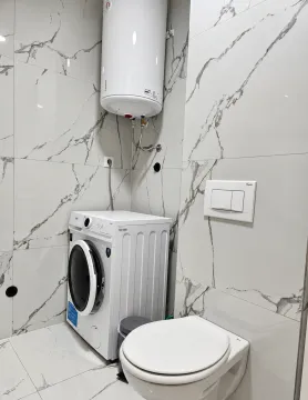 Bathroom with a washing machine, concealed cistern, and water heater. - image 7