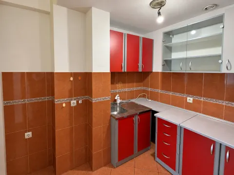 Kitchen with red cabinets and brown ceramic tiles. - image 3