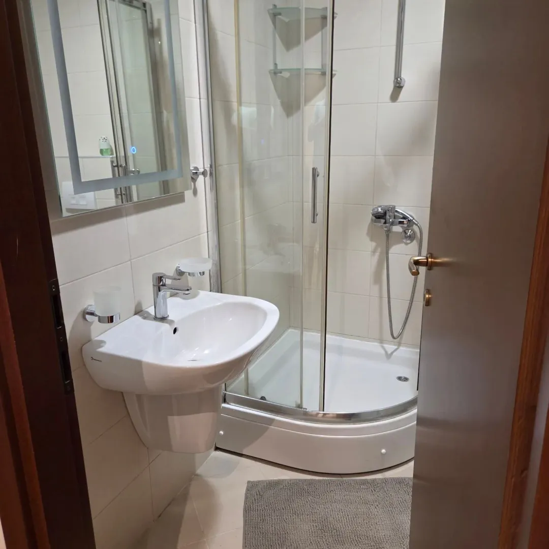 Smaller bathroom with a washbasin, mirror and shower cabin.