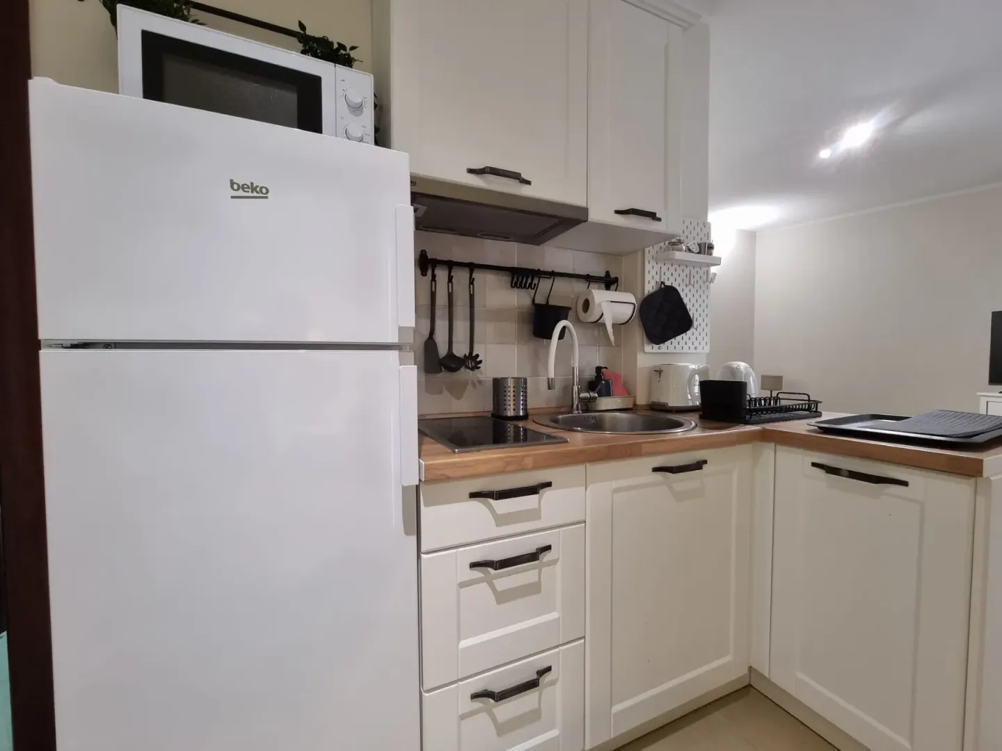 Small white kitchen with a refrigerator and sink.