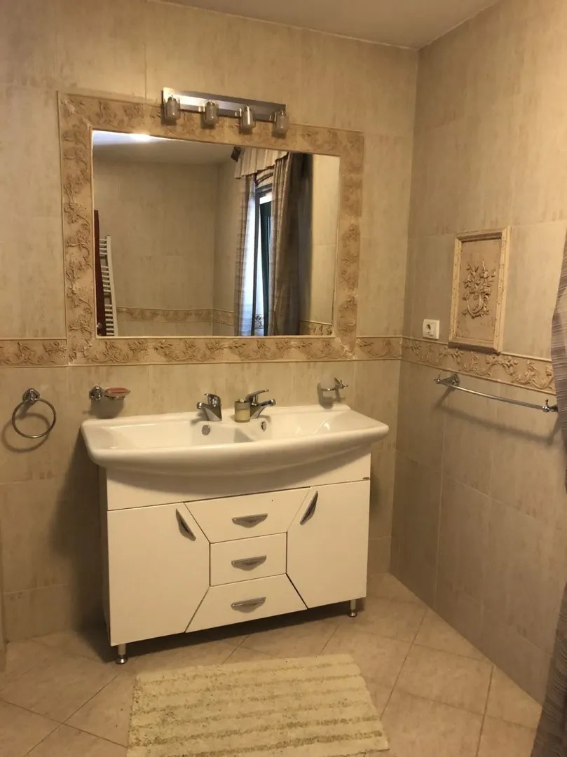 A bathroom featuring a large mirror and a white vanity unit with a sink.
