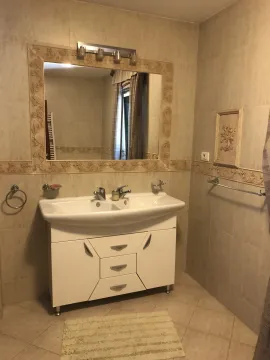 A bathroom featuring a large mirror and a white vanity unit with a sink. - image 25