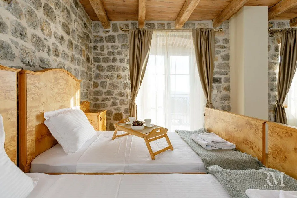 Bedroom with wooden beds, a stone wall, and a wooden ceiling.