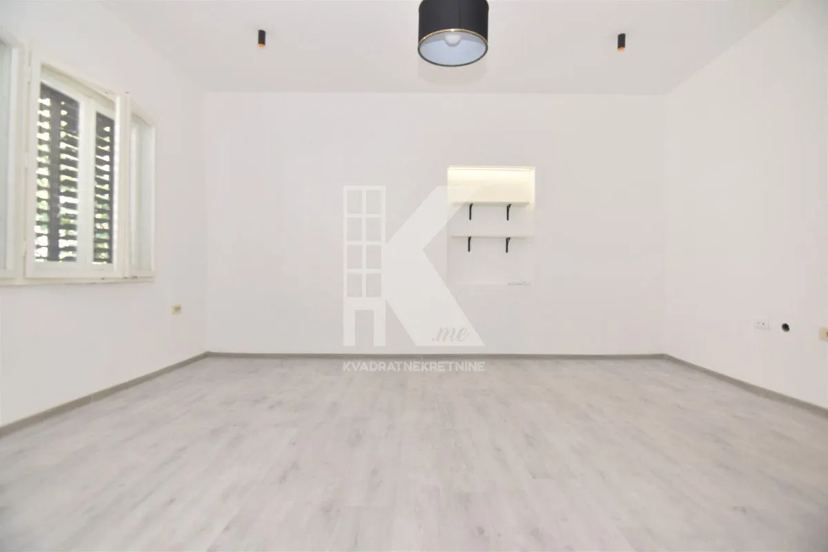 Empty bright room with white walls and light laminate flooring.
