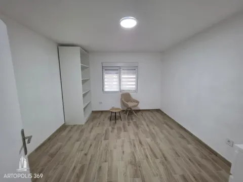 An empty room with white walls, wooden flooring, a wardrobe, and an armchair. - image 13