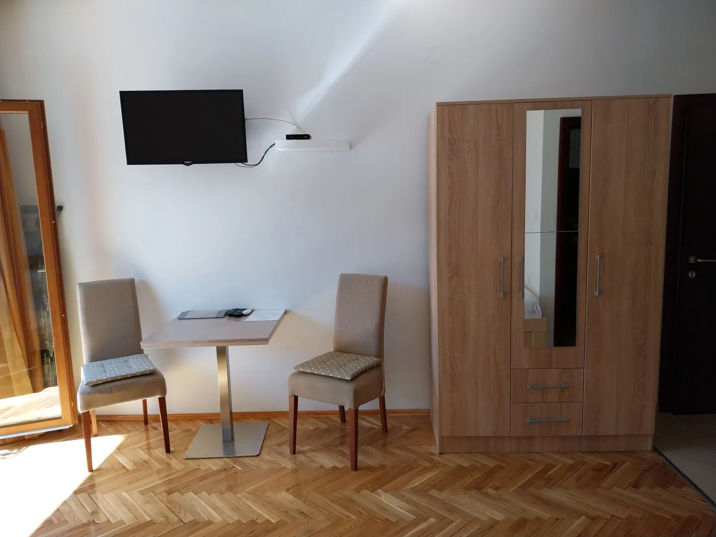 Furnished bedroom with a wardrobe, table, chairs, and TV.