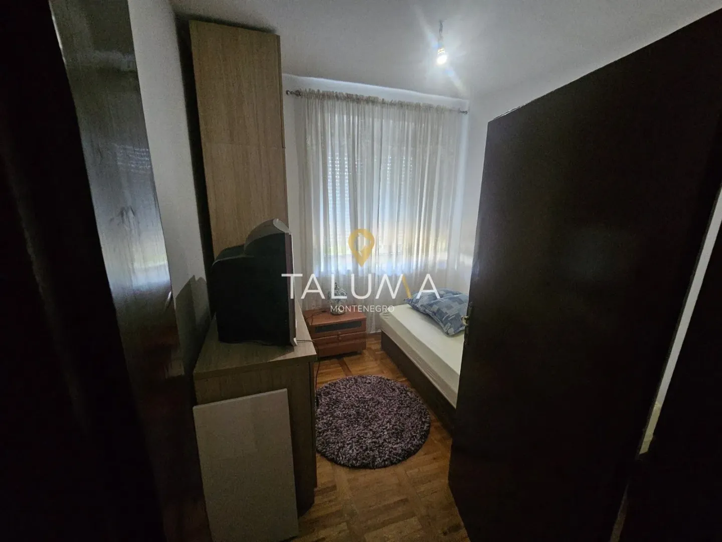 Smaller bedroom with a bed, wardrobe, and television.