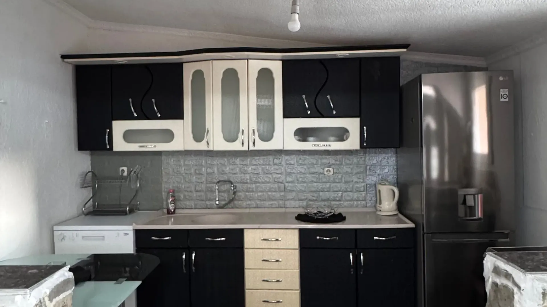 Small kitchen with black and white cabinets and a refrigerator.