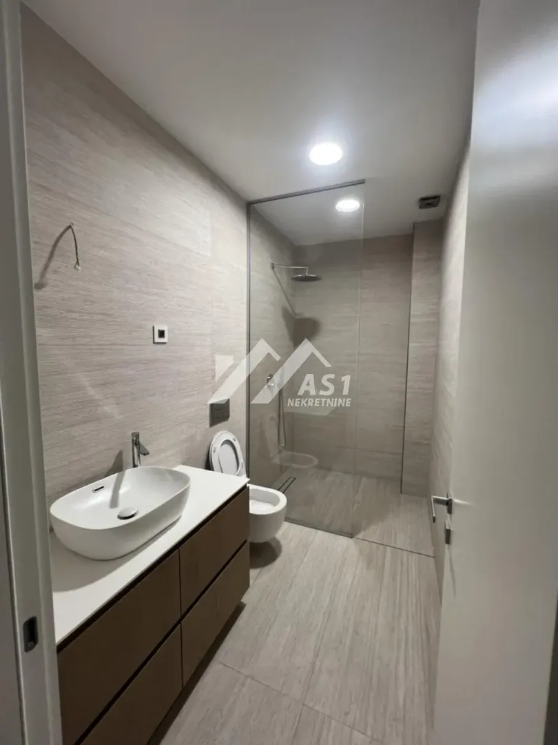 Modernly equipped bathroom with a walk-in shower and a vanity unit.