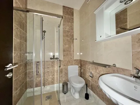 Bathroom equipped with a shower cabin, washbasin, and toilet. - image 7