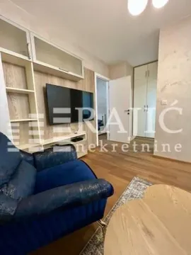 Living room with a blue armchair, TV, and wooden furniture. - image 3