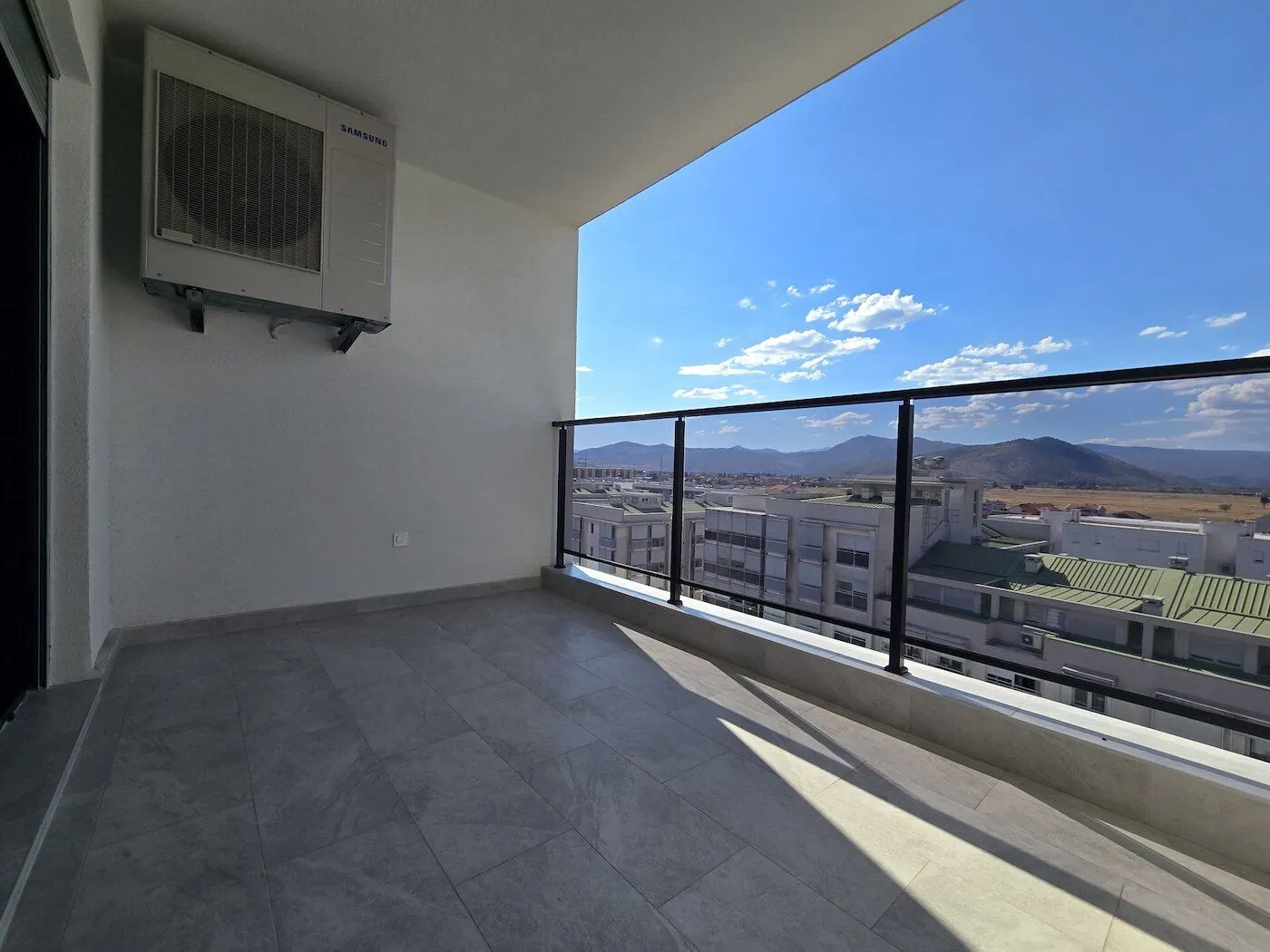 Spacious covered terrace with ceramic flooring and a view of the city and hills.