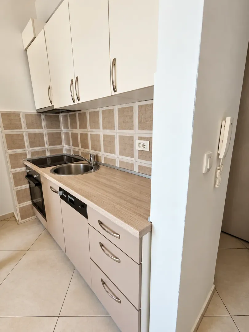 Prikaz dijela kuhinje sa elementima u svijetlim tonovima i radnom površinom.