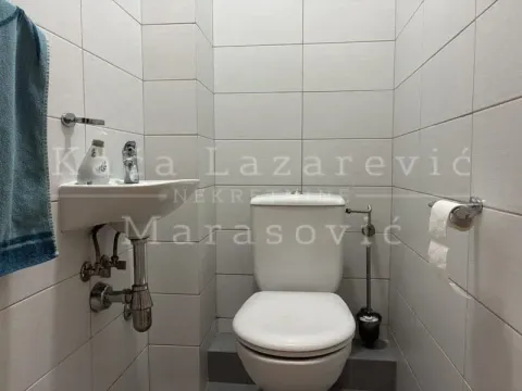 Smaller bathroom lined with light tiles featuring a toilet and washbasin. - image 11
