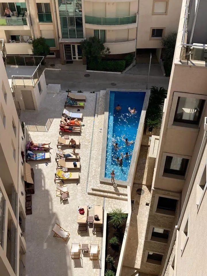 High-angle view of the swimming pool and sunbathing area between residential buildings.