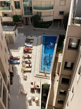 High-angle view of the swimming pool and sunbathing area between residential buildings. - image 12